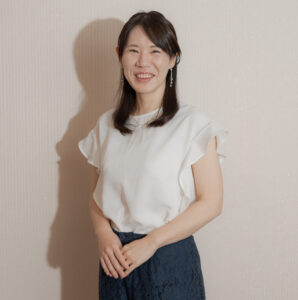 白いトップスとネイビーのスカート姿で微笑むピアノ講師のプロフィール写真